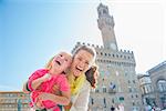 Portrait of happy mother and baby girl in front of palazzo vecchio in florence, italy