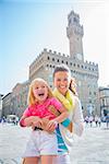Portrait of smiling mother and baby girl in front of palazzo vecchio in florence, italy