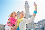 Happy mother and baby girl making selfie in front of palazzo vecchio in florence, italy in florence, italy