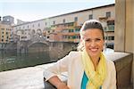 Portrait of smiling young woman near ponte vecchio in florence, italy