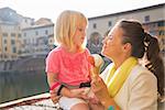 Happy mother and baby girl eating ice cream near ponte vecchio in florence, italy
