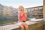 Happy baby girl eating ice cream near ponte vecchio in florence, italy
