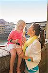 Mother and baby girl eating ice cream near ponte vecchio in florence, italy