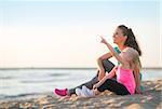 Healthy mother and baby girl pointing while sitting on beach in the evening