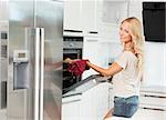 commercial shot of young girl , smiling and cooking with oven , in her luxury kitchen