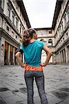 Fitness woman standing in front of uffizi gallery in florence, italy. rear view