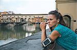 Thoughtful fitness woman standing in front of ponte vecchio in florence, italy