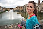 Portrait of happy fitness woman in front of ponte vecchio in florence, italy