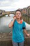 Fitness woman listening music in front of ponte vecchio in florence, italy