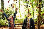 A girl and her brother throwing autumn leaves in the air.