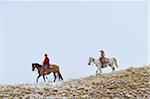 Cowboy with Young Cowboy riding along Horizon with Snow, Rocky Mountains, Wyoming, USA