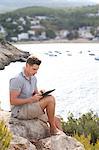 Man sitting with a digital tablet, sea in background