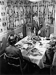 1950s FAMILY OF 5 THANKSGIVING HOLIDAY MEAL MOM DAD MAN WOMAN 3 KIDS BOYS GIRLS AT DINING ROOM TABLE FATHER CARVING TURKEY