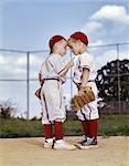 1960s TWO BOYS WEARING LITTLE LEAGUE BASEBALL UNIFORMS HEAD TO HEAD IN ANGRY ARGUMENT