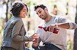 Couple pouring bottle of rose wine in forest