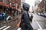 Young woman on rainy pedestrian crossing, Seattle, Washington State, USA