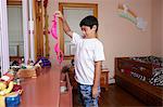 Boy holding up and staring at pink bra in bedroom