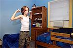 Slim boy flexing arm muscles in bedroom