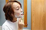 Boy practicing shaving with razor in bathroom