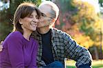 Senior man kissing wife on cheek in garden