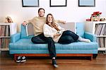 Portrait of young couple on living room sofa with christmas gift