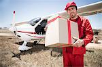 Delivery man carrying parcel off airplane, Wellington, Western Cape, South Africa