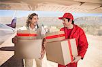 Delivery men carrying parcels off airplane