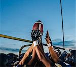 Victorious teenage and young male american football team holding up ball