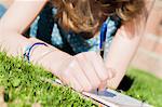 Cropped close up of teenage girl writing in diary in park