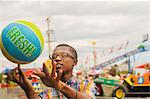 Teenage boy spinning basketball on finger at amusement park