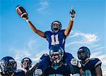 Five teenage and young adult american football players celebrating with shoulder carry