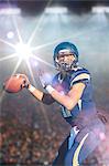 Teenage american footballer holding up ball in stadium