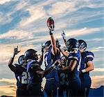 Teenage and young male american football team celebrating together