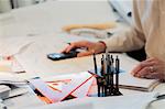 Architect sitting at desk, using calculator, mid section