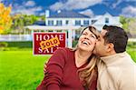 Happy Mixed Race Couple in Front of Sold Real Estate Sign.