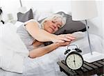 Sleeping woman turn off the alarm clock