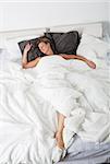 Woman sleeping in a white bedroom environment from high angle view