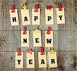 Happy new year lettering with clothes-peg in shape of train and stars on old wooden background