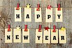 Happy new year lettering with clothes-peg in shape of train and stars on old wooden background