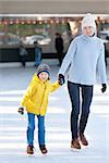 happy mother and her little son having fun ice skating together at winter