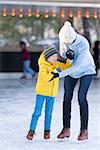 happy mother and her little son having fun ice skating together at winter