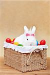 Cute easter bunny with colorful eggs sitting in a basket