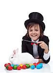 The magic of easter - happy magician boy conjuring a grumpy rabbit and colorful eggs, isolated