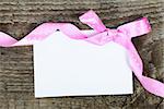 Empty greeting card with ribbon and bow on wooden background