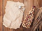 Wine bottle shaped corks, corkscrew and piece of paper for copy space over rustic wooden table background. Top view