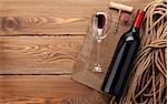 Red wine bottle, wine glass and corkscrew on wooden table background with copy space