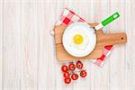 Healthy breakfast with fried egg and tomatoes on white wooden table with copy space