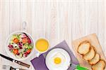 Healthy breakfast with fried egg, toasts and salad on white wooden table with copy space