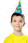 Portrait of eight years boy with birthday cap looking up on white background