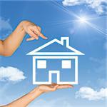 House icon on hand. Second hand points to house. Background of blue sky, clouds and sun